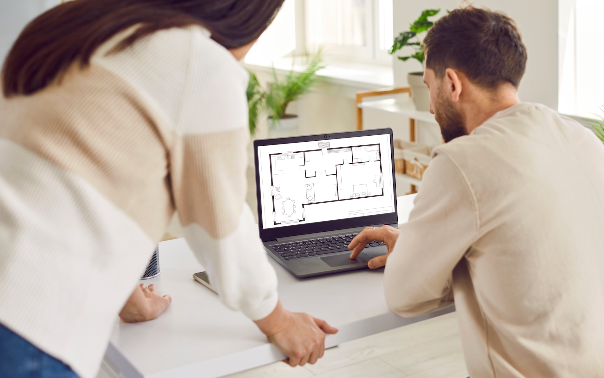 Couple looking at blueprint of architecture plan apartment set discussing engineering floor plan.