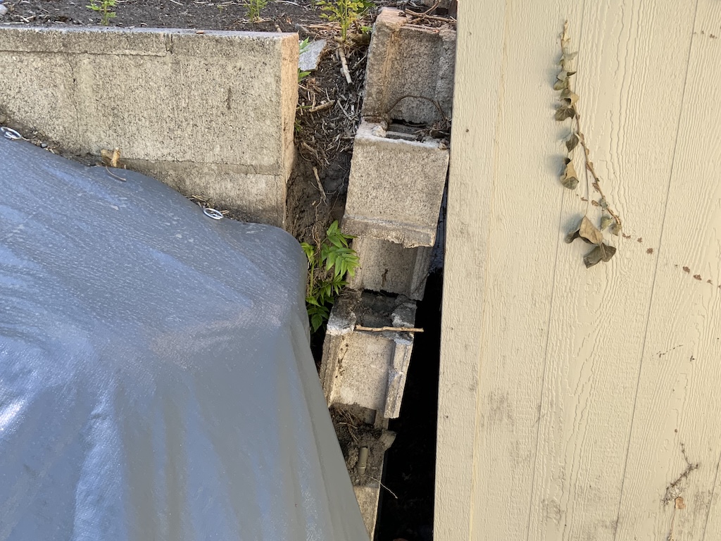 Failing cinderblock retainer wall separating at corner